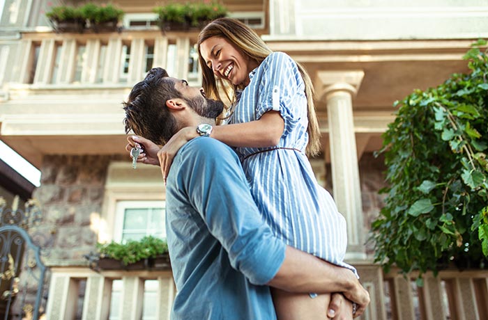 First home buyers standing in front of their new home